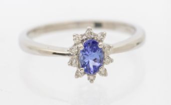 A tanzanite and diamond platinum set cluster ring. comprising an oval mixed cut tanzanite approx 5 x