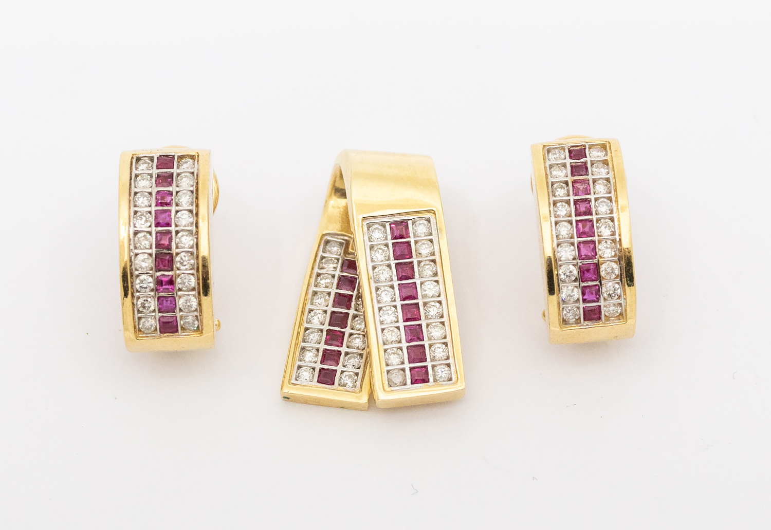 A ruby and diamond 14ct gold pendant, ribbon like form with a central row of calibre cut rubies