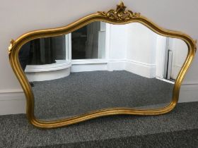 A large kidney shaped gilt framed over mantle mirror with scallop detail. Width 151cm, height 106cm.