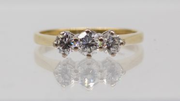 A three stone diamond and 18ct gold ring comprising three round brilliant cut diamonds, claw set,