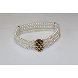A three row cream-white cultured button pearl bracelet with a 9ct yellow gold diamond set bar clasp.