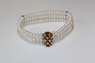 A three row cream-white cultured button pearl bracelet with a 9ct yellow gold diamond set bar clasp.