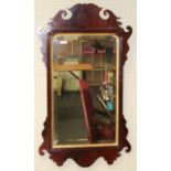 A George II walnut and parcel gilt mirror, the upright bevelled plate enclosed by a scrolled