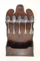 An 18th century oak spoon rack, the shaped back with recesses for five spoons, over a pocket