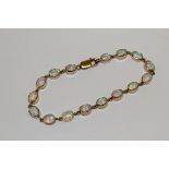 A 9ct yellow gold opal line bracelet, set with 16 cabochon opals, bezel set. Approximate length