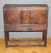 A dwarf oak standing livery cupboard, the oblong top over a pair of carved panel doors and lunette