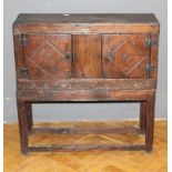 A dwarf oak standing livery cupboard, the oblong top over a pair of carved panel doors and lunette