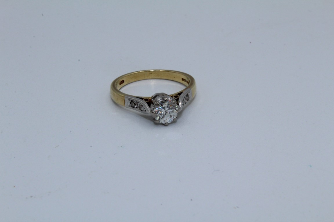 An 18ct diamond solitaire ring. Set with a principal stone of an estimated 0.65 carats. Shoulders