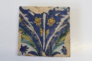 A Safavid style glazed pottery tile decorated with leaves, fronds and flowers in polychrome,