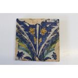 A Safavid style glazed pottery tile decorated with leaves, fronds and flowers in polychrome,