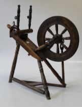 An 18th century beech spinning wheel of typical form, raised on turned legs and a triangular base,