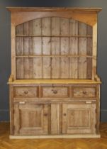 A pine dresser, early – mid 20th century, the boarded plate rack with a moulded cornice over two