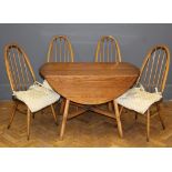 An Ercol light elm drop flap dining table, the oval top raised on fluted splayed square supports,