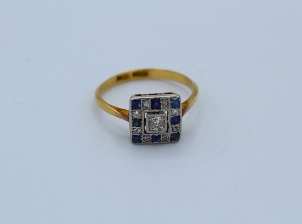 An Art Deco diamond and sapphire panel ring. Stamped "18ct + plat" to the shank.