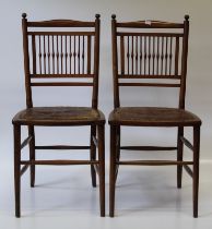 A pair of Liberty style Arts and Crafts walnut and beech side chairs, each having embossed leather