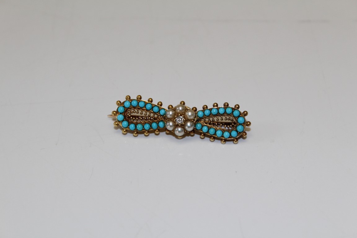 A Victorian turquoise, seed pearl and diamond archaeological revival style bow brooch. Set with