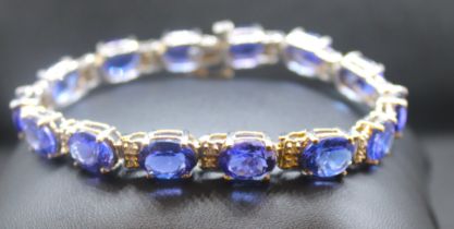 A tanzanite and diamond set 14ct white gold line bracelet, comprising a row of fourteen claw set