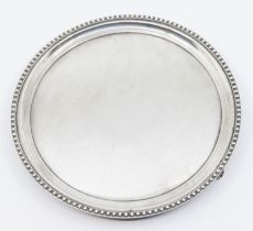 A Georgian style silver waiter, plain circular with beaded border, on three supports, hallmarked