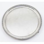 A Georgian style silver waiter, plain circular with beaded border, on three supports, hallmarked