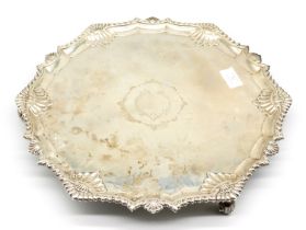 A George V silver salver with shell and scroll border, on three scrolled feet, stylised letter C