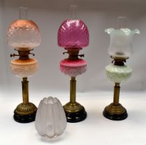 A small collection of late 19th/early 20th century oil lamps, all with moulded pink, light green and