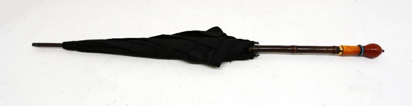 An early 20th Century black silk taffeta parasol with faux bamboo handle, gilt metal straps, the