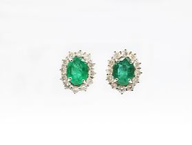 A pair of emerald and diamond set 18ct white gold cluster earrings, comprising an oval mixed cut