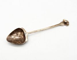 AE Jones - an Arts & Crafts silver spoon, having stylised flower shaped terminal, a long thin stem