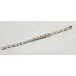 A 14ct. white gold and diamond bracelet, fashioned from rectangular and sunburst links, each of