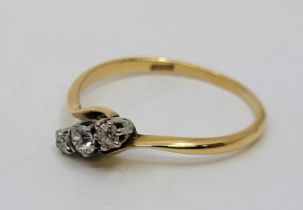 An 18ct. gold three stone diamond cross-over style ring, set row of three graduated diamonds (the