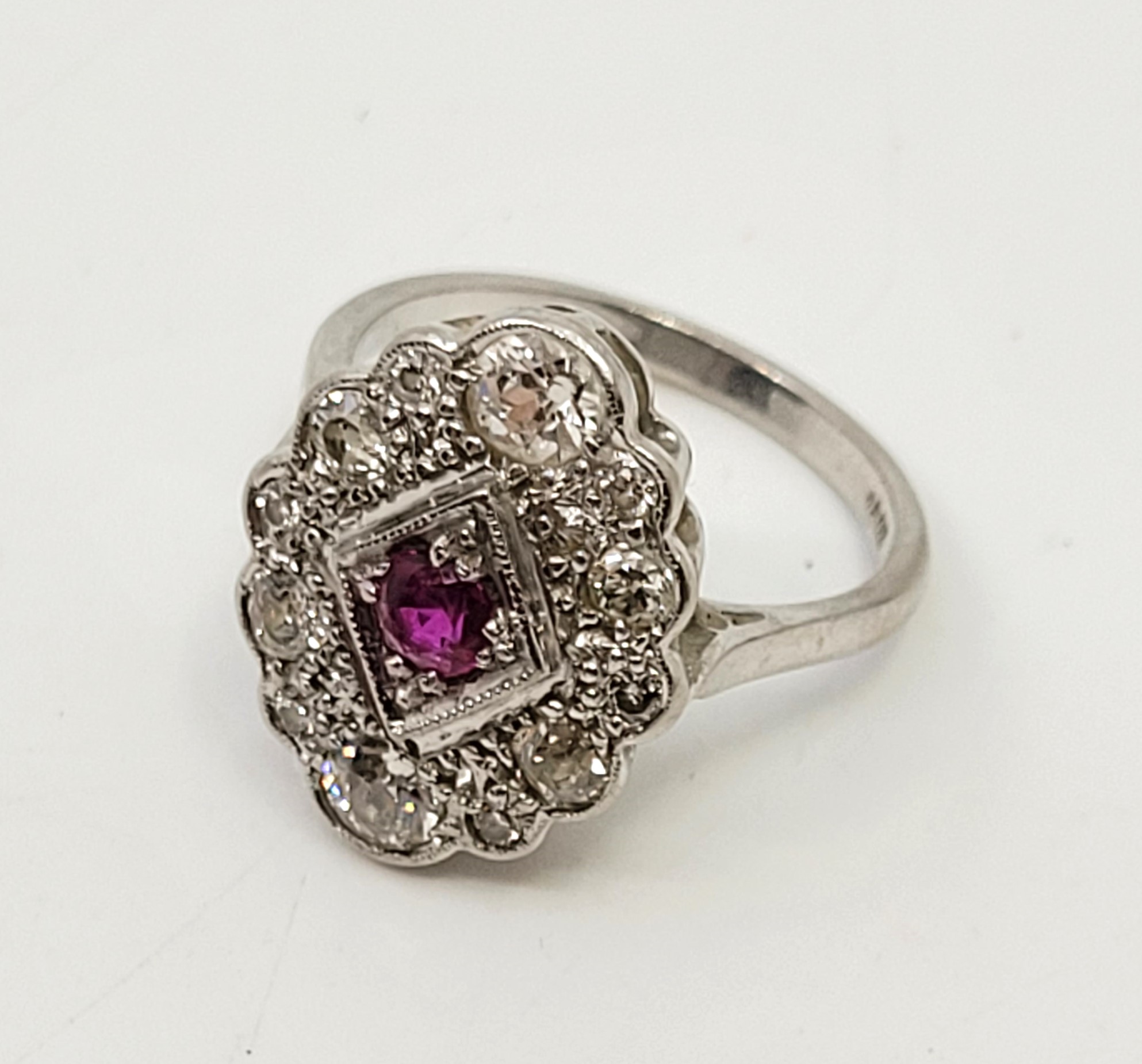 An 18ct. white gold, diamond and ruby ring, in the Art Deco style, having lobed oval mount set mixed