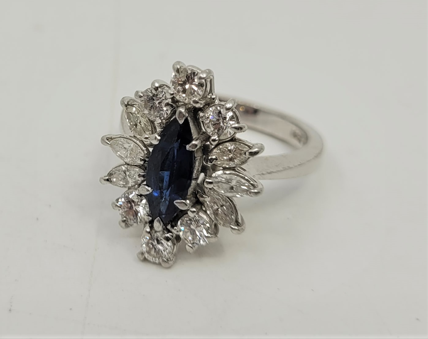 An 18ct. white gold, platinum, sapphire and diamond ring, set marquise cut blue sapphire to centre