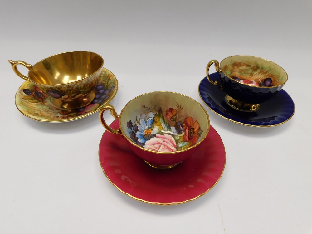 A collection of three Aynsley cabinet cups and saucers, all signed by artists, fruit design and