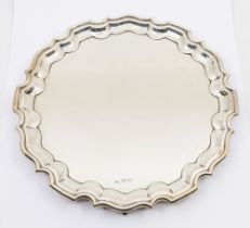 A late Edwardian silver salver, three scrolled feet and pie crust edging, hallmarked by Walker &