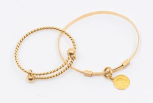 Two gold children's expander bangles, including an 18ct gold version suspending a charm, weight