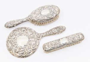 A Queen Elizabeth II three piece silver dressing table set consisting of mirror, hand brush and