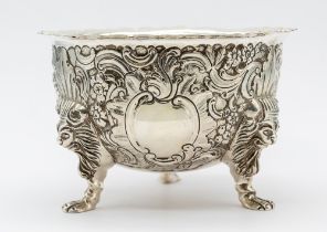 A George V Irish silver three footed sugar bowl, with ornate embossed and engraved floral, fruit and