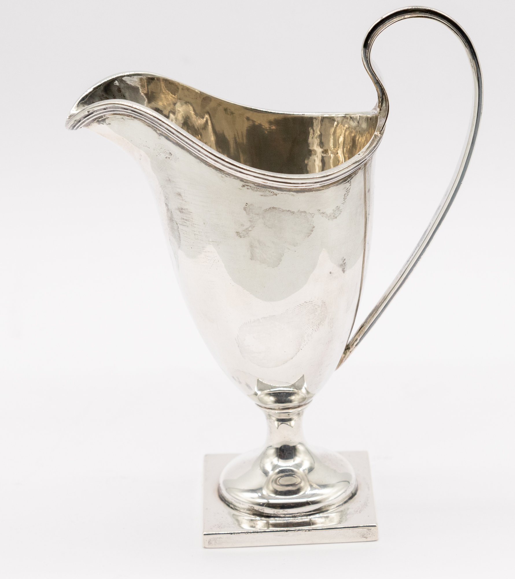 A late Victorian silver helmet shaped cream jug, square footed base and curved handle, hallmarked by