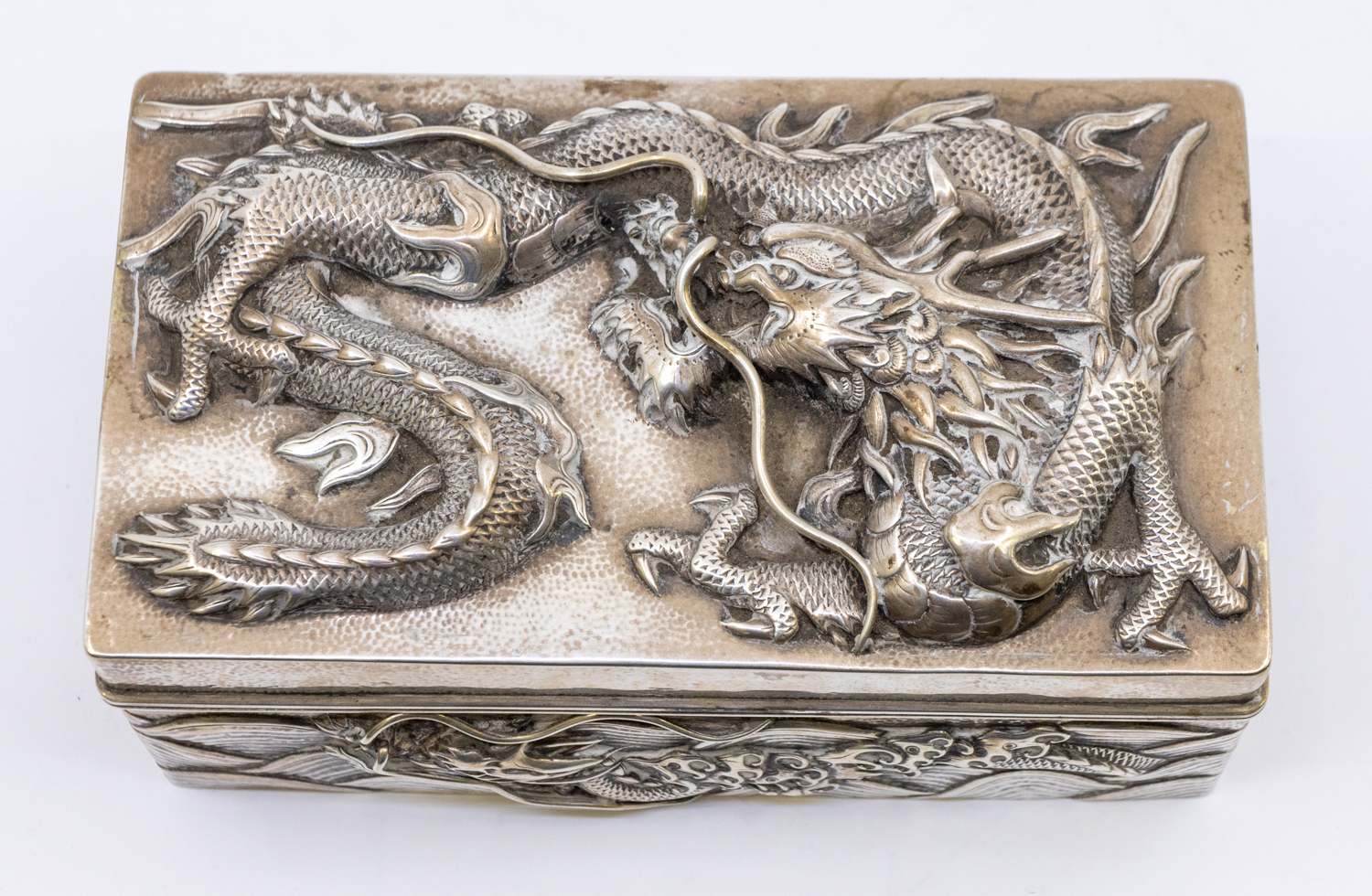 A Chinese silver cigarette box, with relief dragon design to top and all sides, slight planishing to - Image 2 of 4