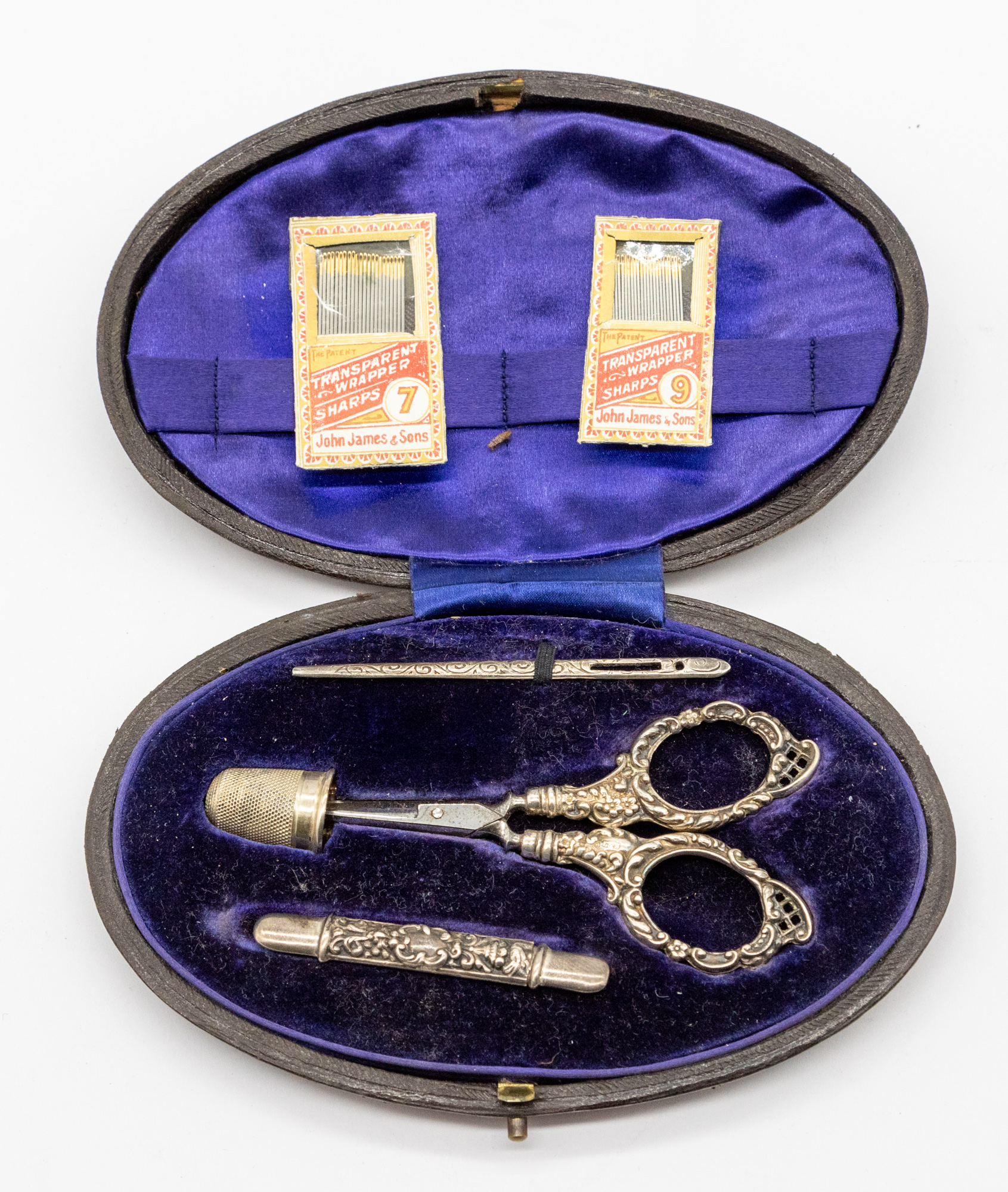 A cased late Victorian silver sewing set consisting of threading needle, scissors, thimble and