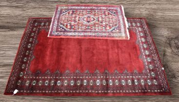 A mid 20th Century deep red hand knotted Pakistani rug with crab border detail aong with a small