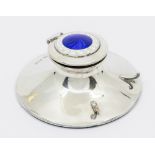 A George V silver and enamel ink well, on circular base with two curved supports for pen holder, the