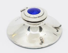 A George V silver and enamel ink well, on circular base with two curved supports for pen holder, the