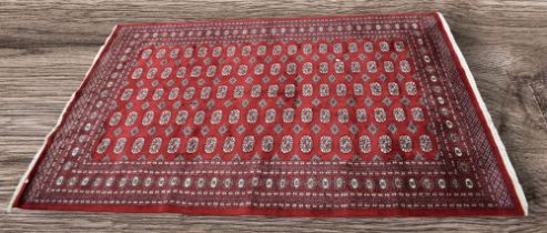 A large late 20th Century red ground rug/carpet from Pakistan, 9ft x 6ft.