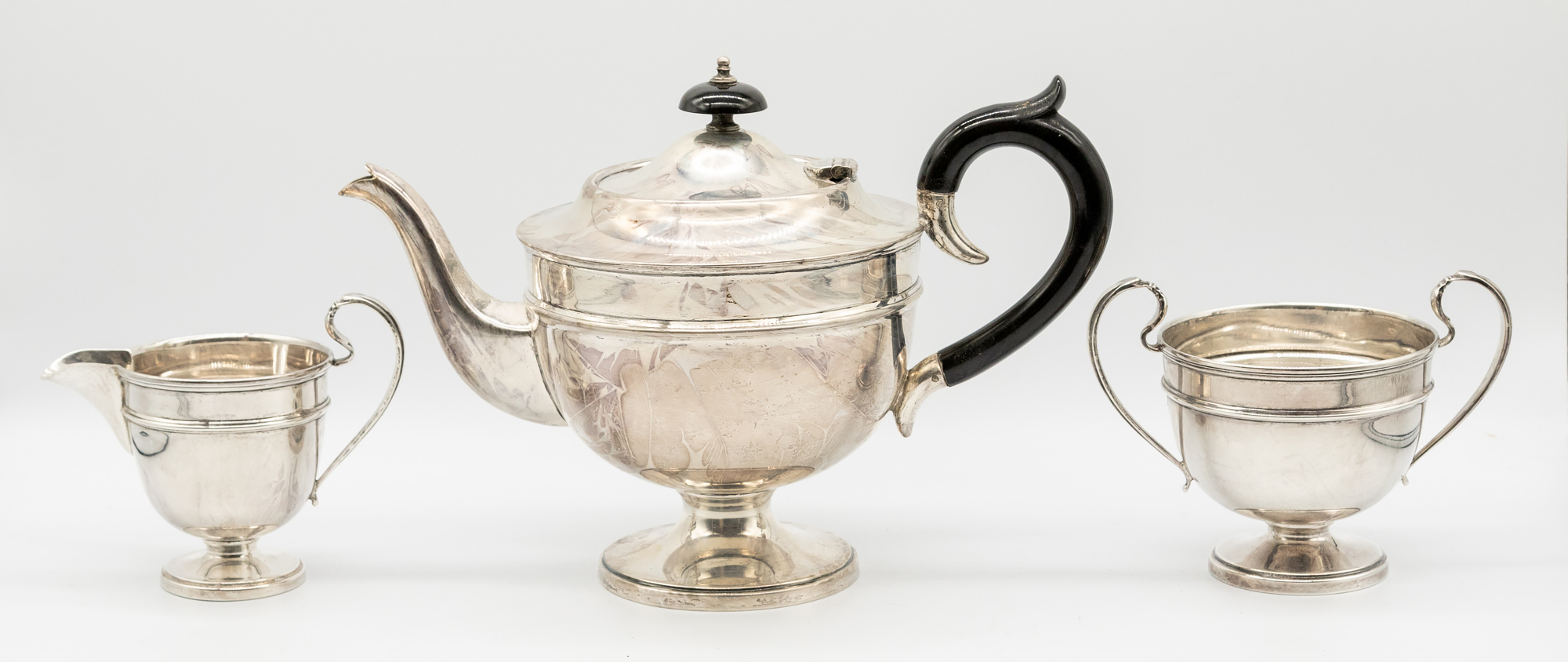 A matched George V silver three piece tea set consisting of tea pot, twin handled sugar bowl and