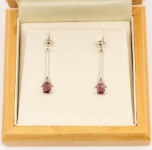 A pair of ruby and 9ct white gold drop earrings, rod like drops with pear cut ruby terminals, rubies