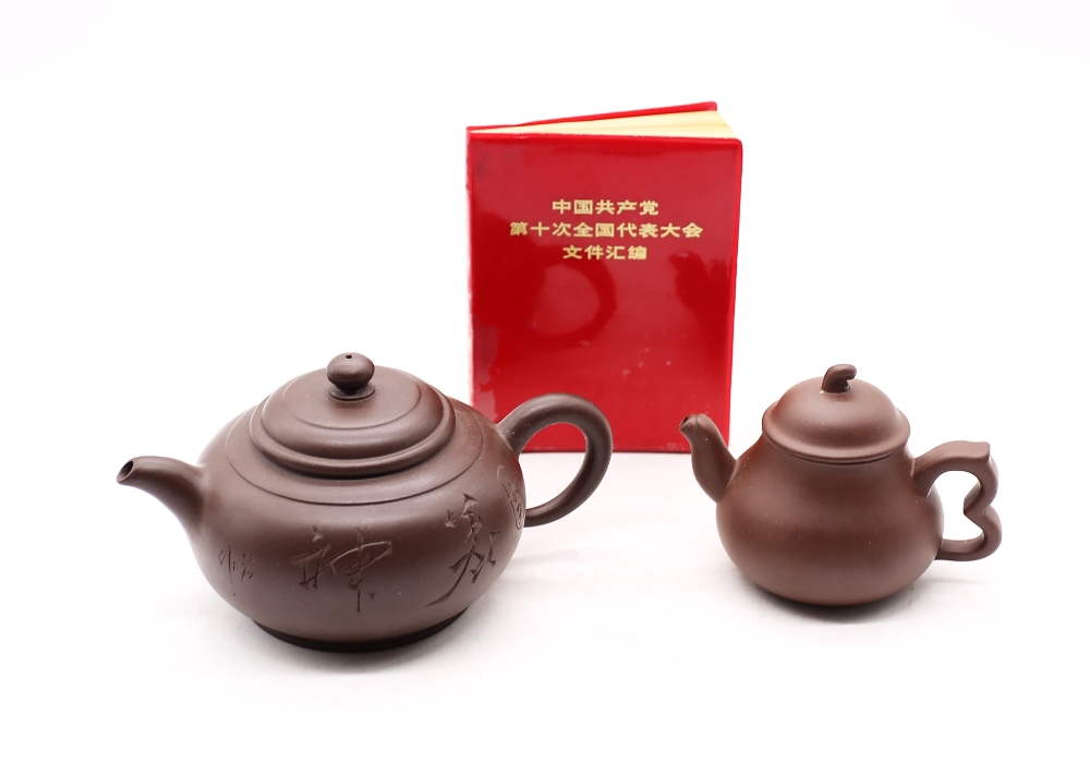 A Yixing clayware Zhi Sha tea pot along with another clayware tea pot and Chinese little red book.