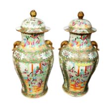 A pair of late 19th century Cantonese famille rose lidded vases, with elephant trunk handles and