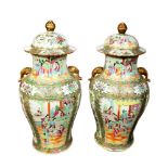 A pair of late 19th century Cantonese famille rose lidded vases, with elephant trunk handles and