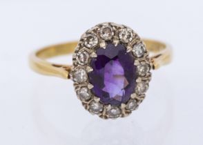 An amethyst and diamond 18ct gold ring, comprising an oval mixed cut amethyst within a border of